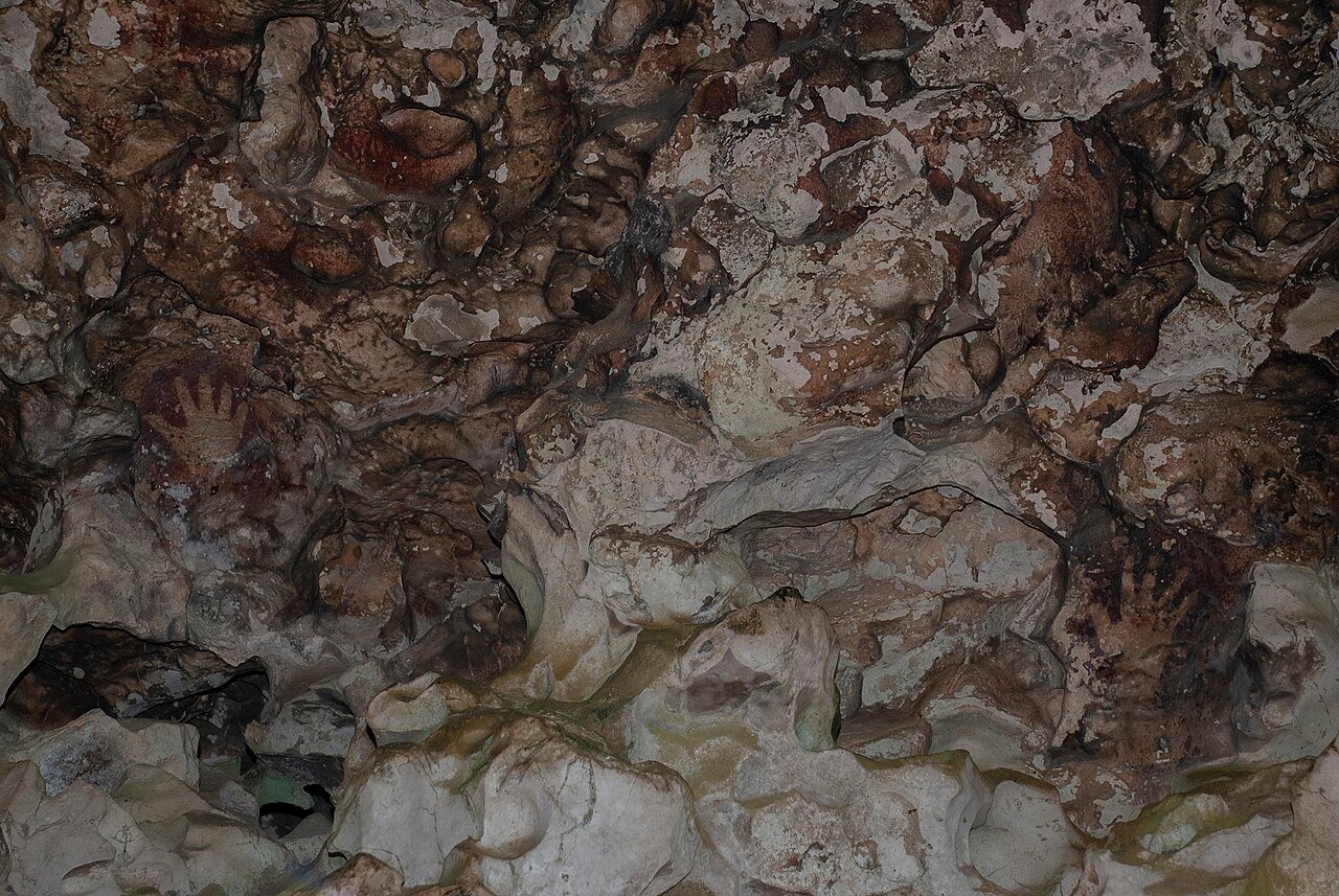 Negative hand-print rock art in the Leang-Leang cave – rahmatrahimnur, CC BY-SA 4.0, via Wikimedia Commons