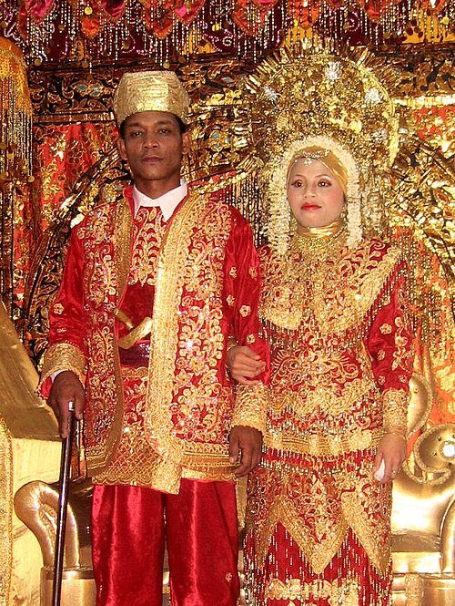 A Minangkabau couple during their wedding ceremony – Michael J. Lowe, CC BY-SA 2.5, via Wikimedia Commons