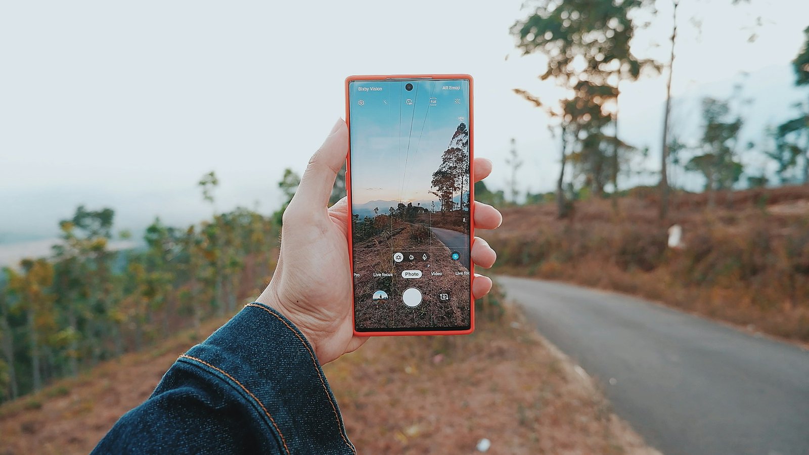 A person photographing an Indonesian landscape with their phone